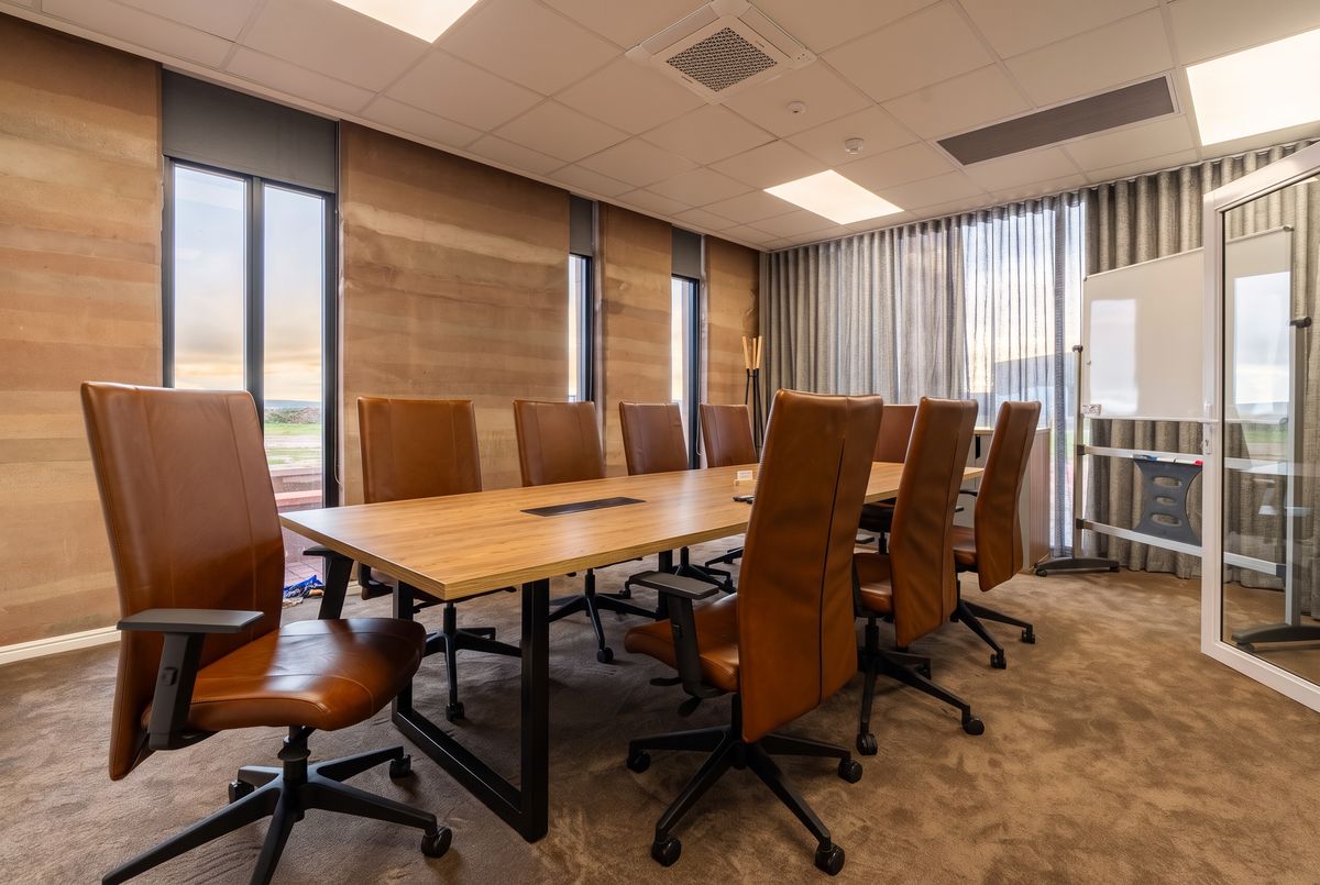Boardroom with a timber table and tan leather chairs, furnished by Nuwave