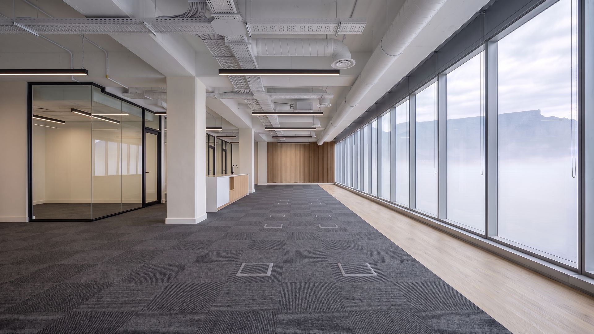 The same floor with charcoal carpet tiles, an oak walkway, a timber slat wall and built in joinery