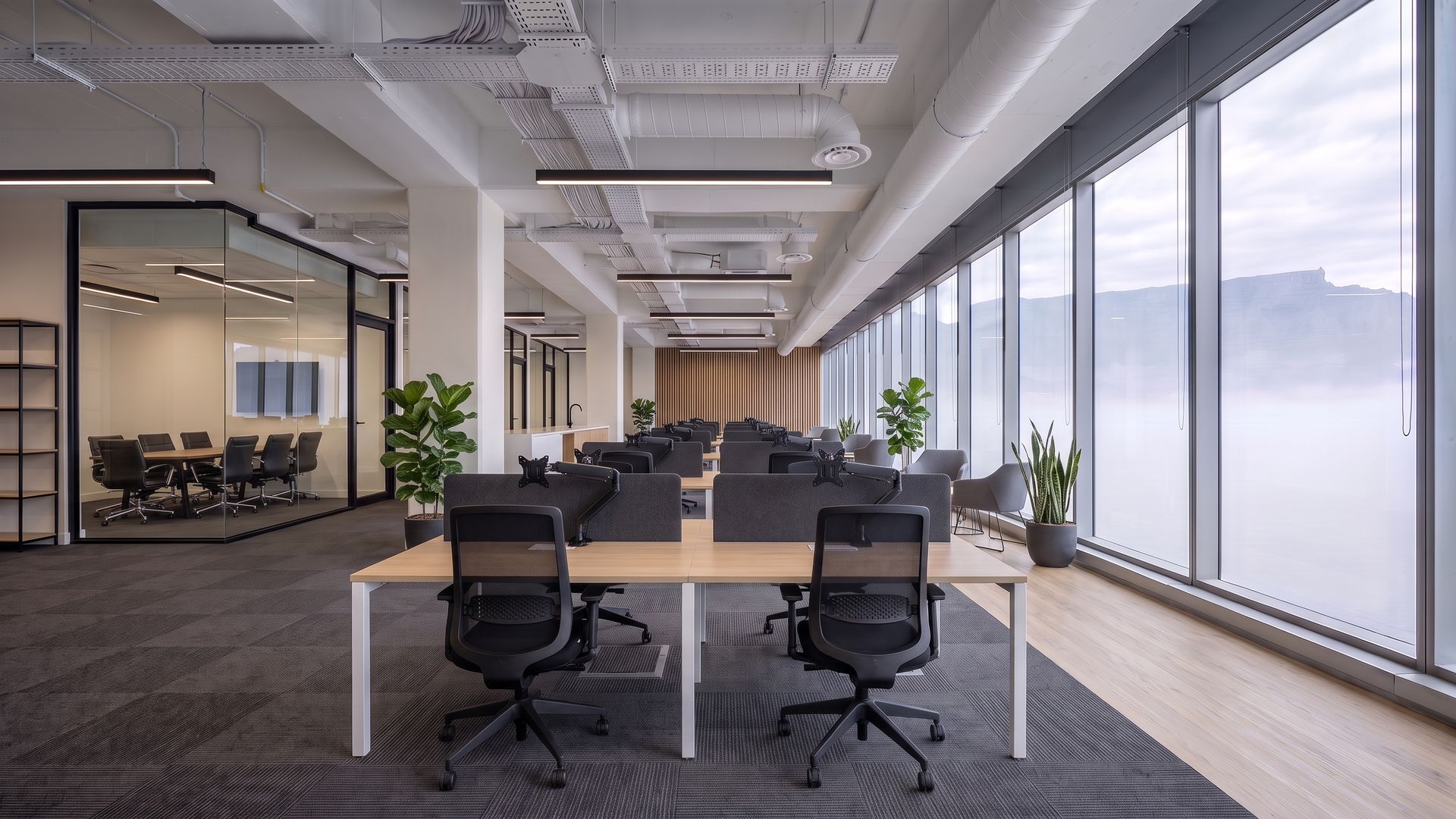 The same floor furnished with bench workstations, task chairs, a boardroom table and plants