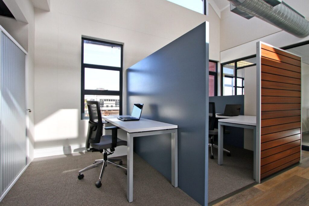 A workstation with a grey screen against the timber slat wall at Yield Capital, by Nuwave