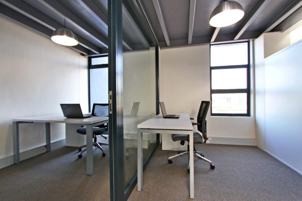 Two facing desks with task chairs in a glass fronted office at Yield Capital, by Nuwave