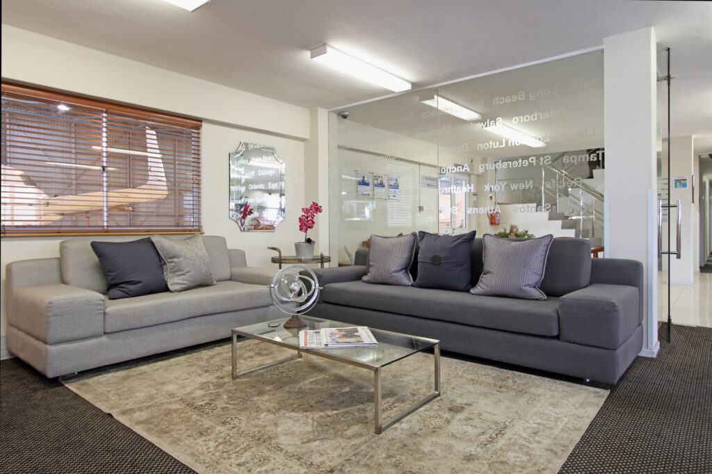 The passenger lounge with grey sofas and a glass table at Signature Flight Support, Cape Town Airport, by Nuwave