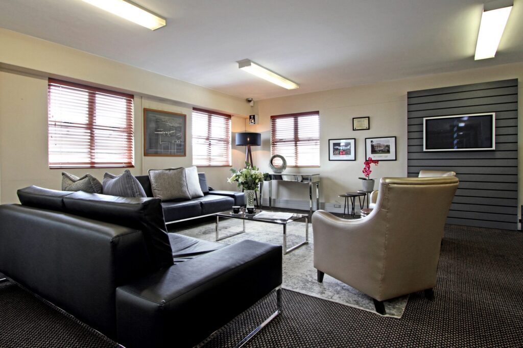 A lounge with a black leather sofa and armchairs at Signature Flight Support, Cape Town Airport, by Nuwave