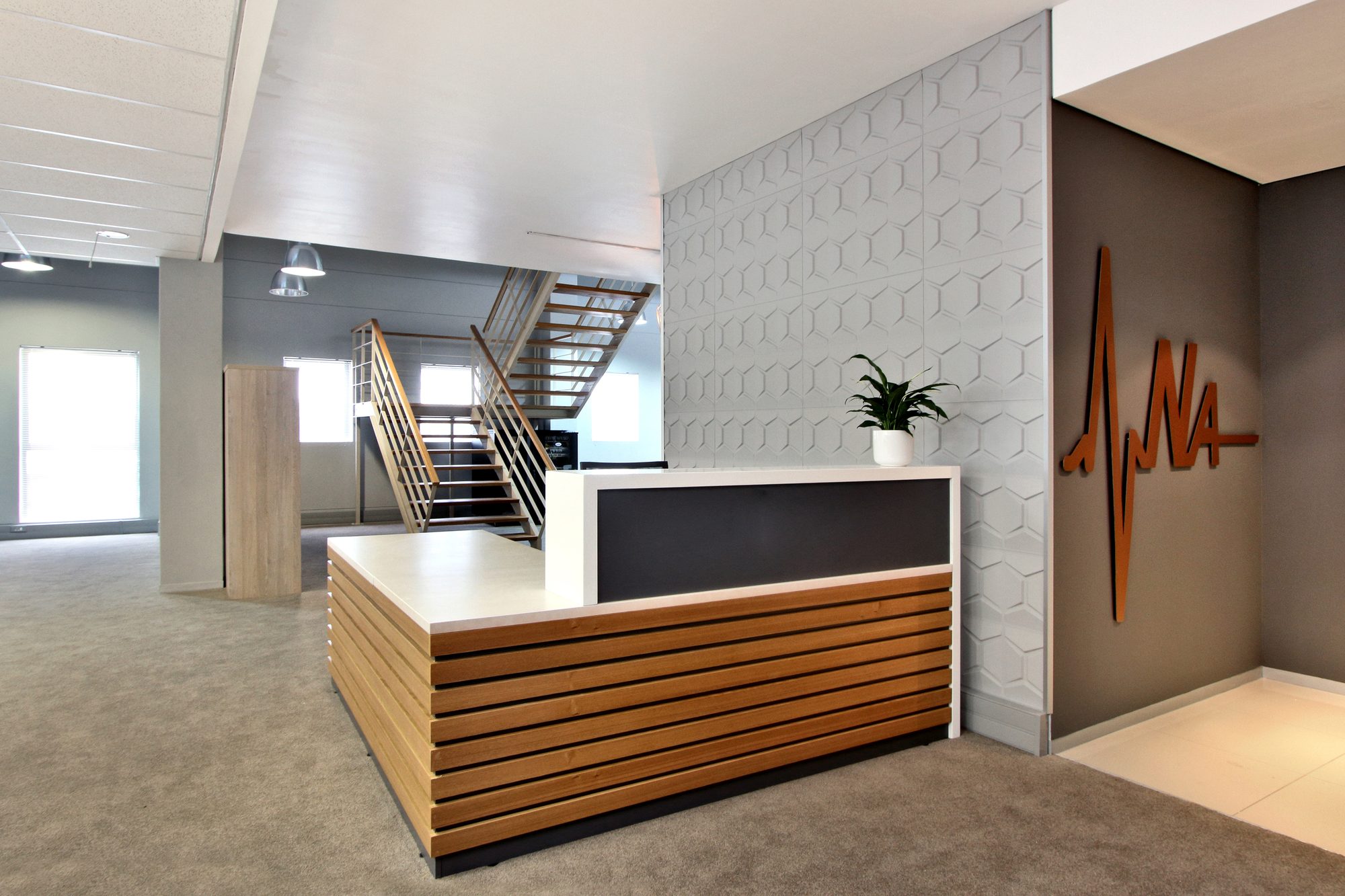 The timber slat reception counter and heartbeat logo at New Approach Medical, furnished by Nuwave