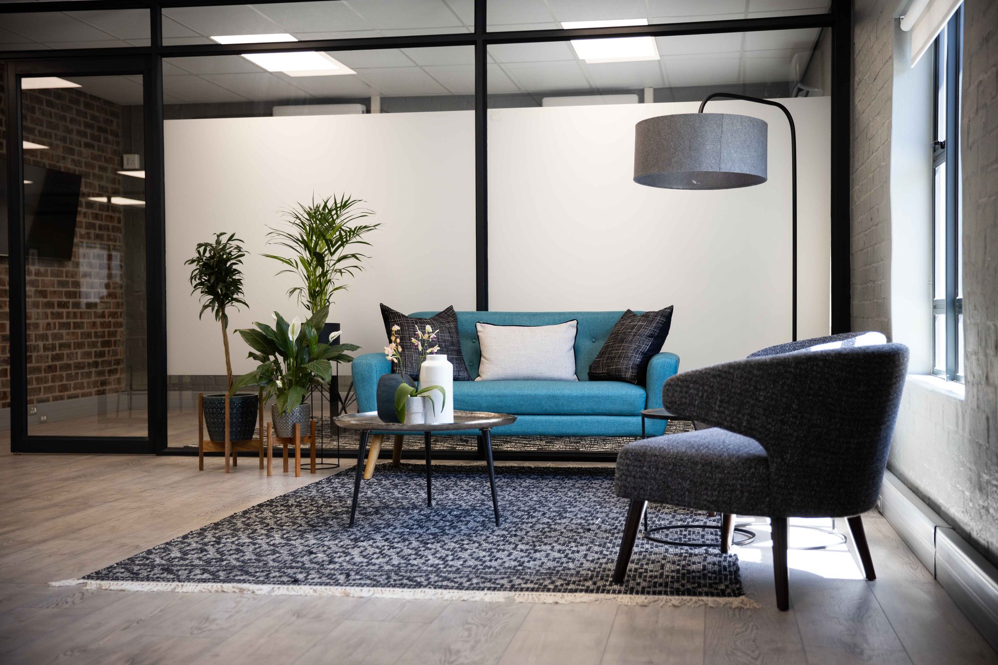 Reception lounge with a blue sofa and grey armchairs at Vancula Agency in Cape Town, furnished by Nuwave