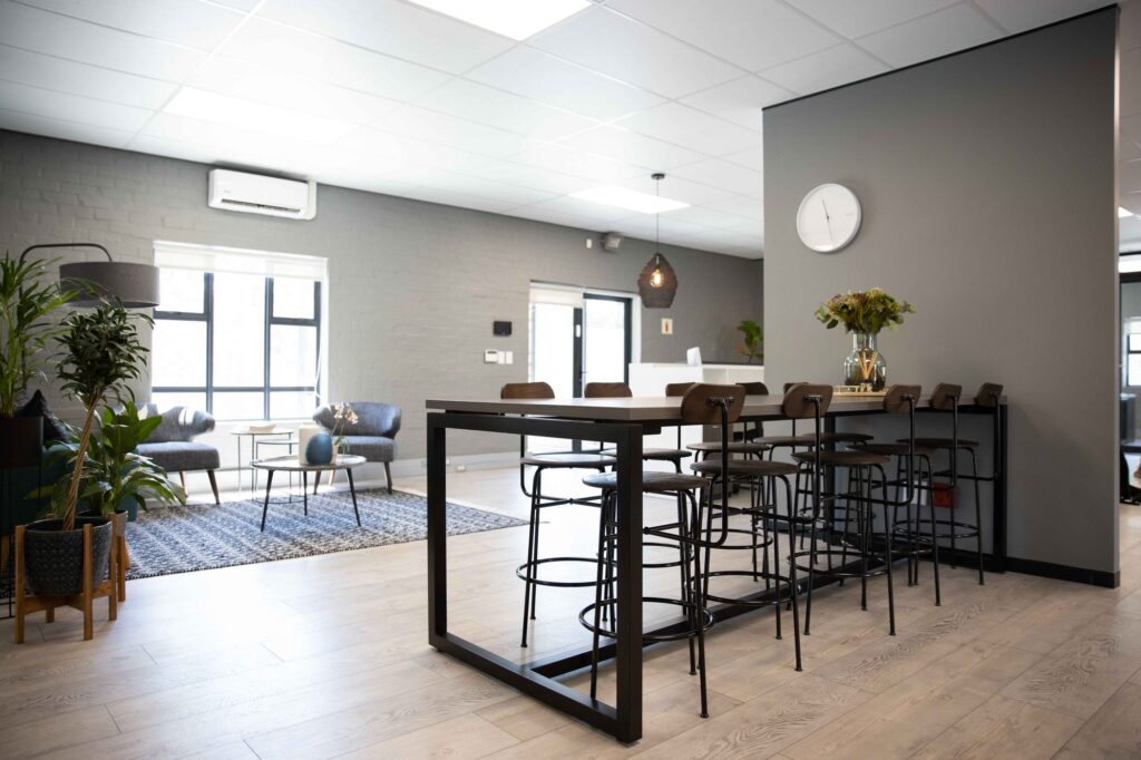 A high table with stools under pendant lights at Vancula Agency in Cape Town, by Nuwave