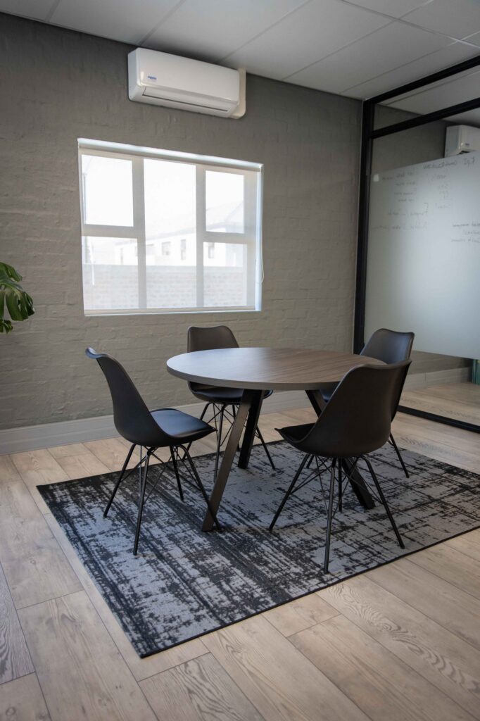 A round meeting table with chairs on a rug at Vancula Agency in Cape Town, by Nuwave