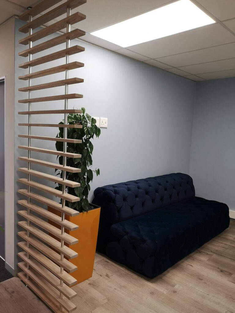 A timber slat screen dividing the floor with a blue sofa behind at Nordex Energy, by Nuwave