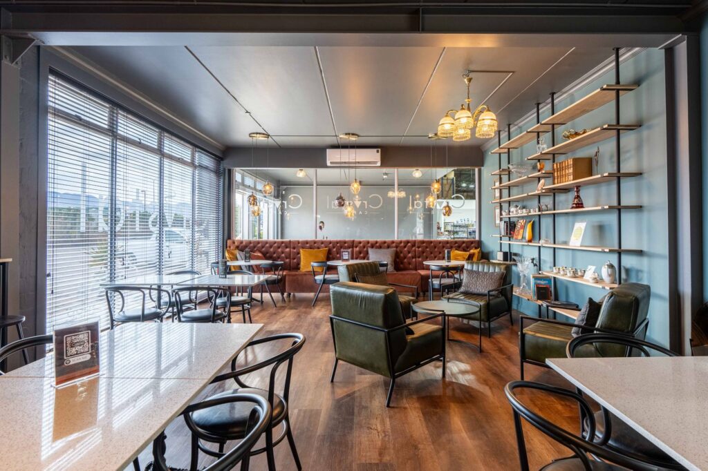 The Crystal Cafe with green leather armchairs, round tables and shelving, furnished by Nuwave