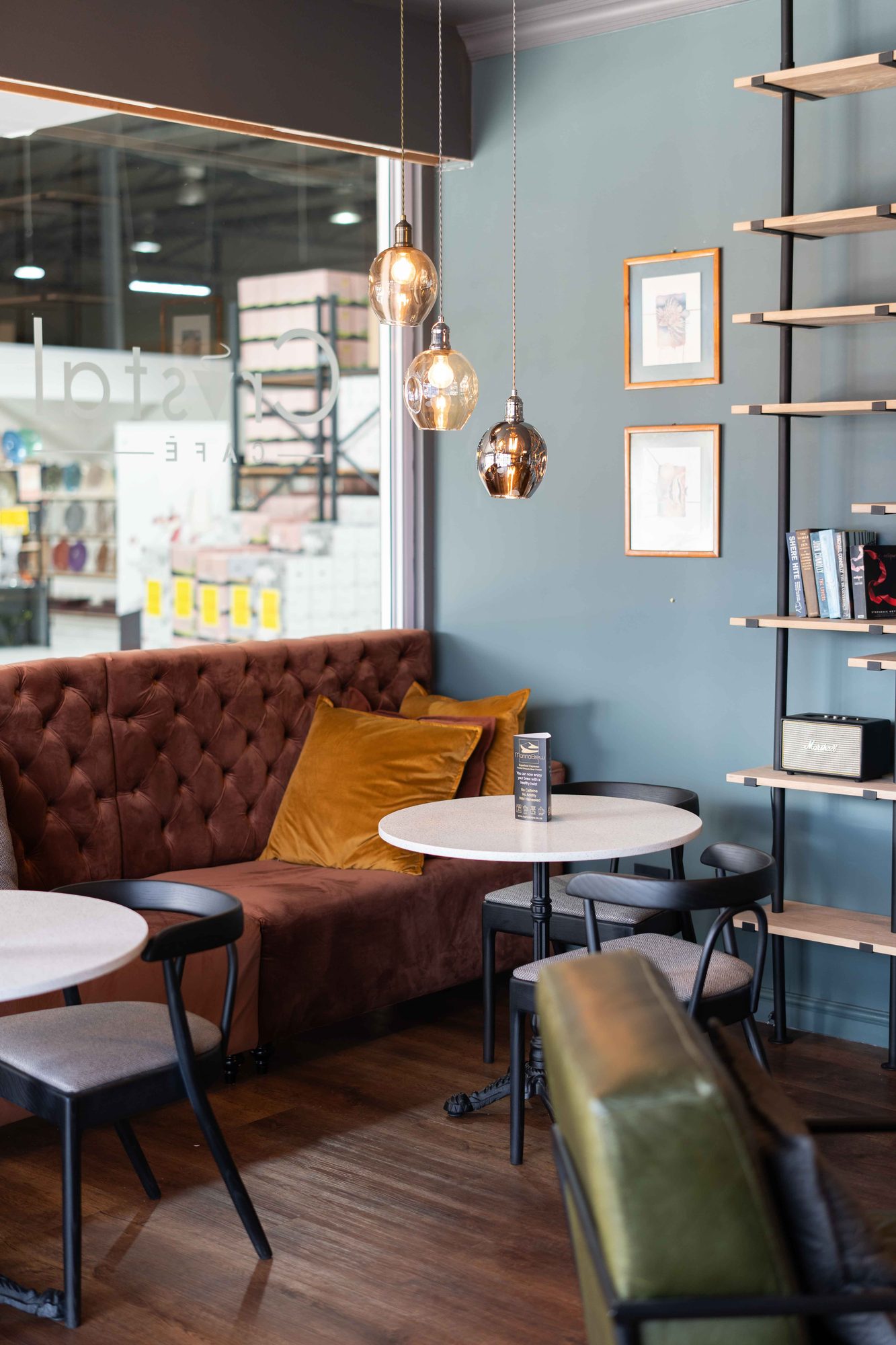 A chesterfield sofa with a round table and pendant light in the Crystal Direct cafe, by Nuwave