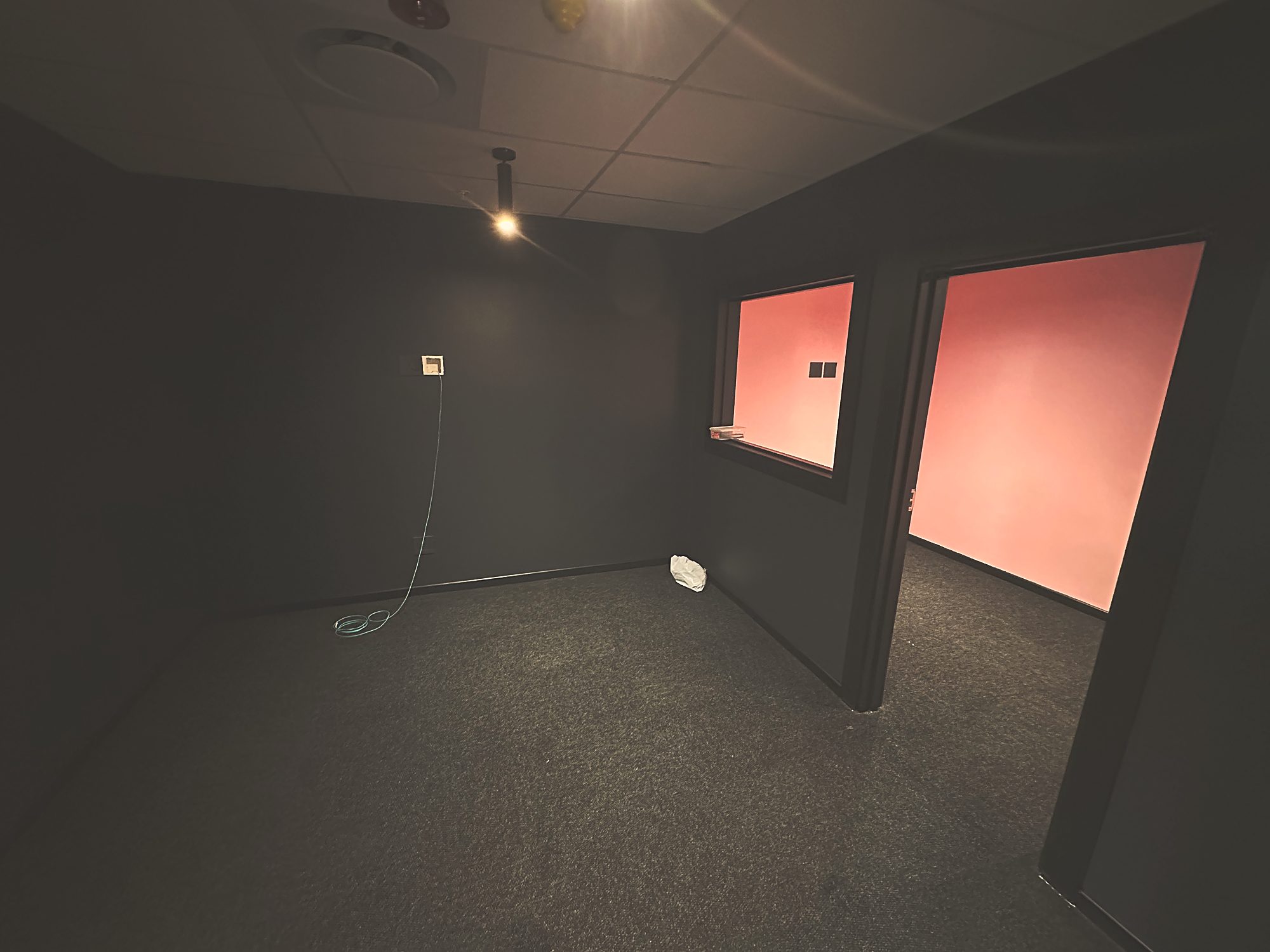 A darkened edit suite with a pink wall panel at Polycat Visual Effects, by Nuwave