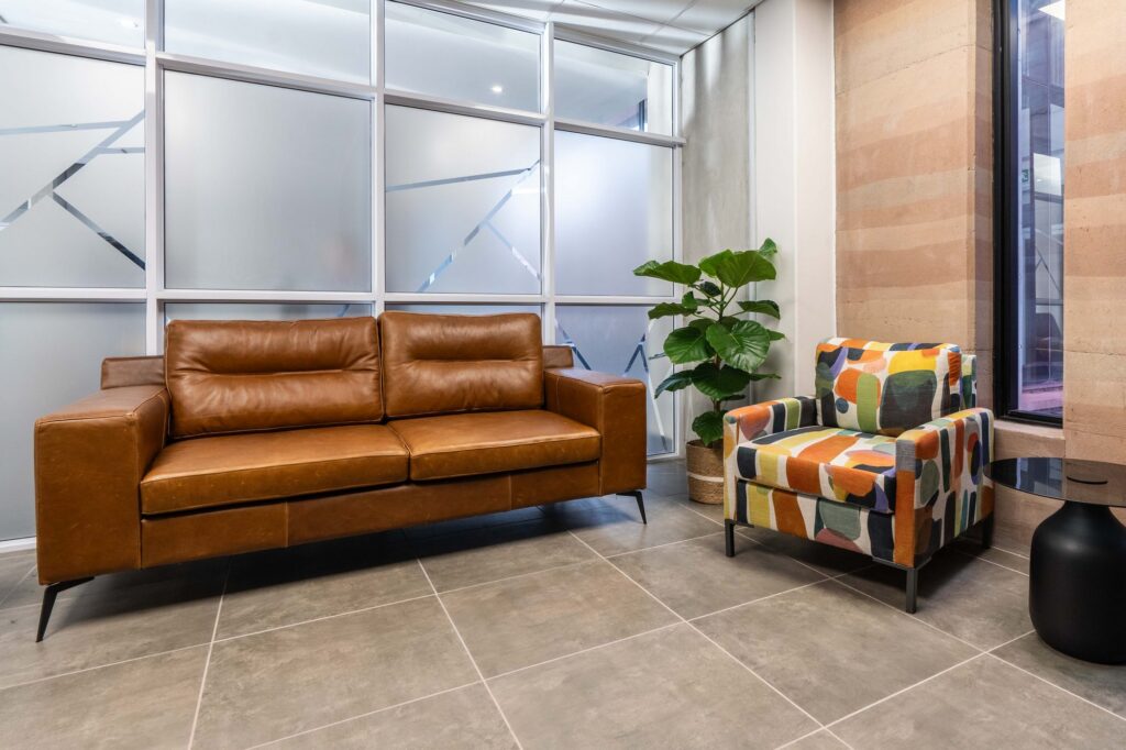 A tan leather sofa and patterned armchair in the Oil Spill Response reception, by Nuwave