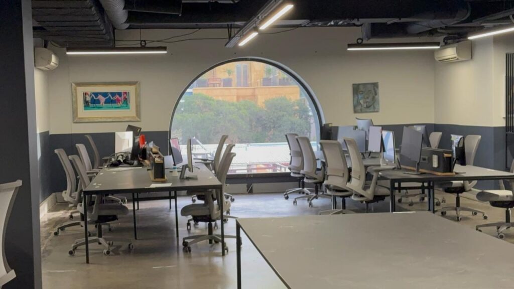 Workstations beside the arched feature window at Rain's Cape Town office, furnished by Nuwave