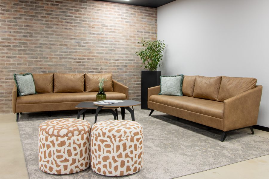 Tan leather couches and patterned ottomans in an office lounge